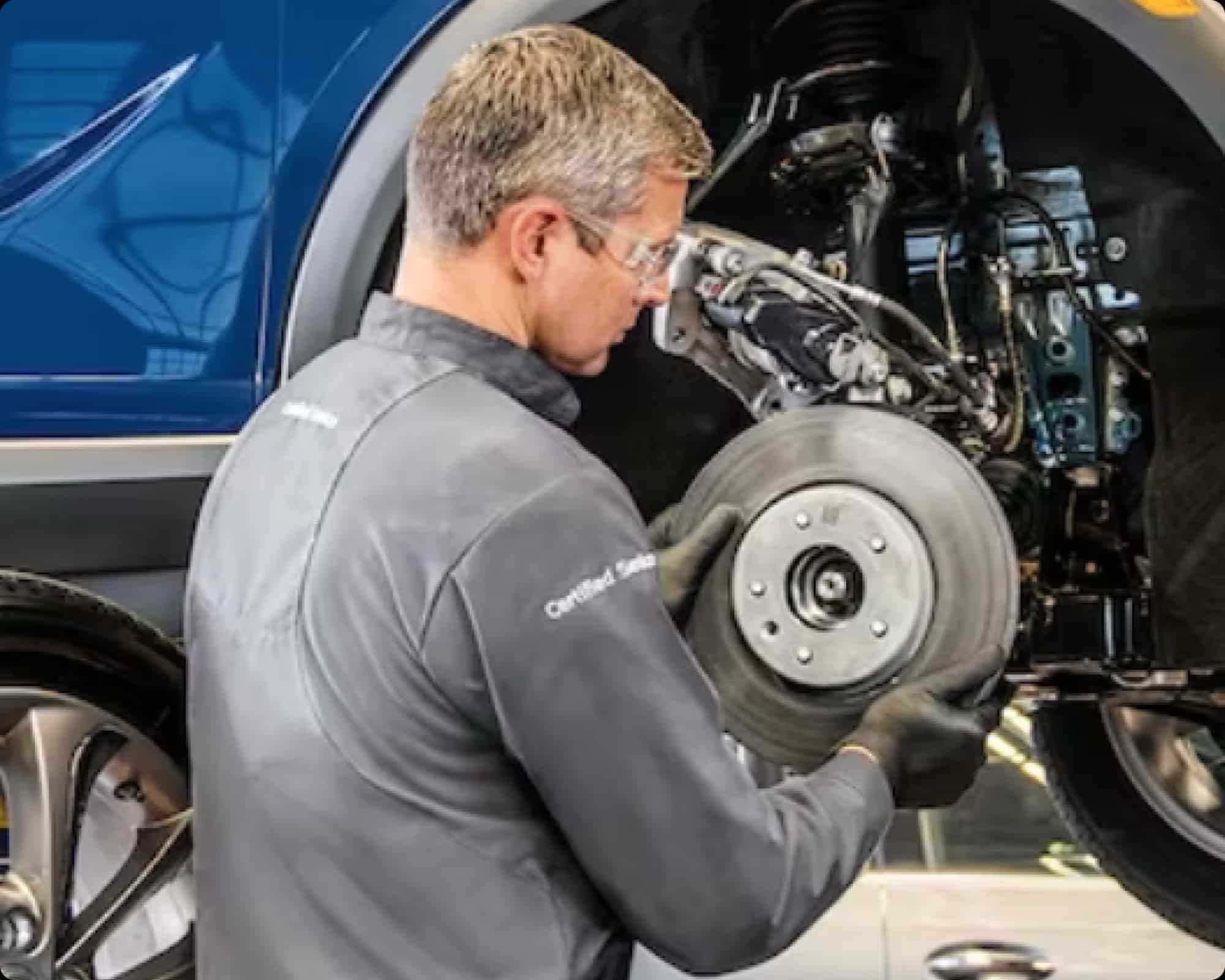 Mechanic inspecting a car brake disc at an auto repair shop.