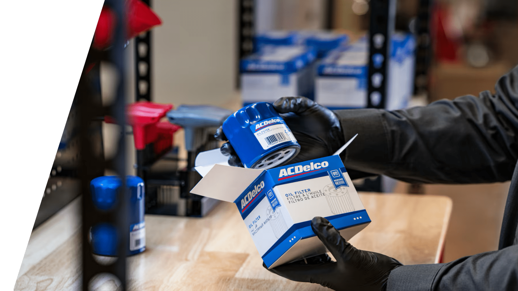 Person holding an ACDelco oil filter box on a workbench, with more filters in the background.