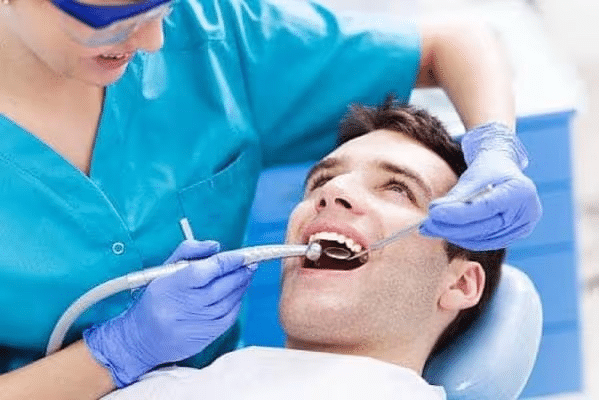 Dentist examining a smiling patient with dental tools in a clinic setting.